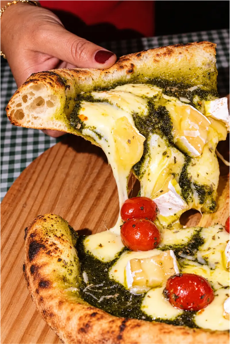 Fatia de pizza napoletana com pesto, queijo brie e tomate confit, de borda alta e alveolada